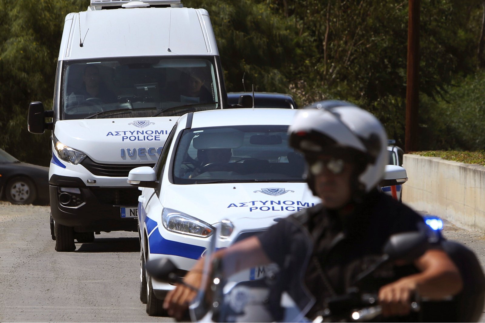 A motorcyclist police officer escorts and guards the police van carrying Army Captain Nicholas Metaxas from the court to the Cypriot central prison in capital Nicosia, Cyprus, Monday, June 24, 2019.  A Cypriot army captain on Monday tearfully apologized to the families of seven foreign women and girls for the "unjust pain" he has caused them after pleading guilty to a dozen charges of premeditated murder and kidnapping.  (AP Photo/Petros Karadjias)