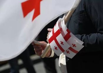 epa08444565 A man holds small Georgian national flags while marking the 102th anniversary of the Georgian Independence in Tbilisi, Georgia, 26 May 2020. The Act of Independence of Georgia was adopted on 26 May 1918.  EPA-EFE/ZURAB KURTSIKIDZE