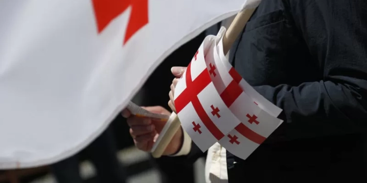 epa08444565 A man holds small Georgian national flags while marking the 102th anniversary of the Georgian Independence in Tbilisi, Georgia, 26 May 2020. The Act of Independence of Georgia was adopted on 26 May 1918.  EPA-EFE/ZURAB KURTSIKIDZE